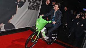 Virou Bob Dylan! Timothée Chalamet chega em première de novo filme usando bicicleta